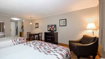 A hotel room with two beds, a desk, a television, and a chair.
