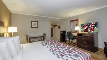Habitación de hotel con cama, escritorio, silla, televisor y cómoda.