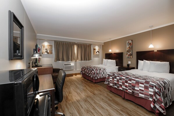 A hotel room with two beds, a desk, a chair, a TV, and a window with curtains. - Red Roof Inn & Suites Herkimer (Herkimer)