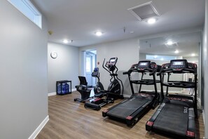 Uma academia em casa com esteiras, elíptico e bicicleta ergométrica.