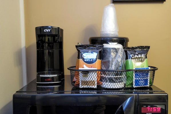 A coffee maker, a water dispenser, and a basket with coffee pods on a countertop.