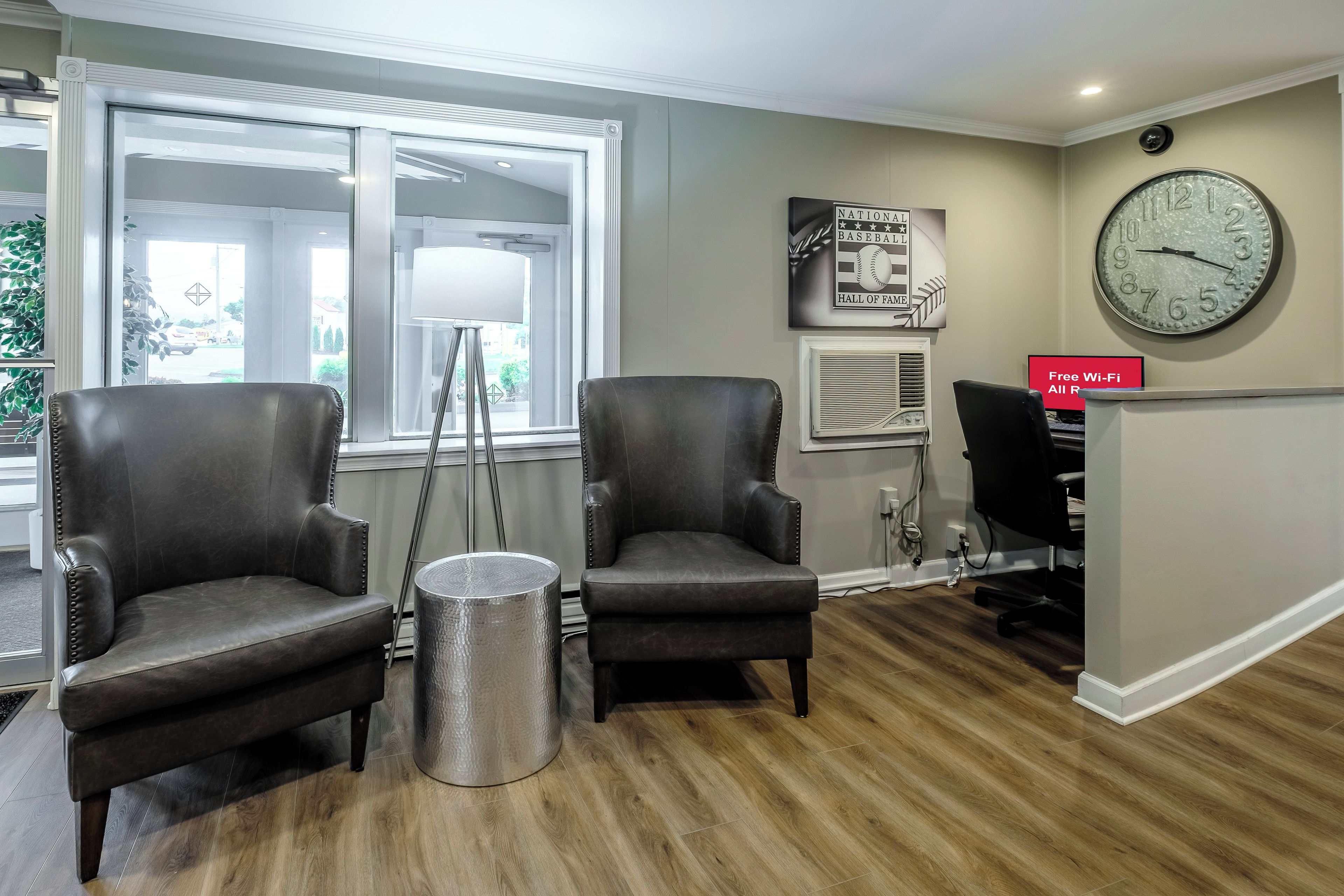 A reception area with two leather chairs, a floor lamp, a clock, and a sign indicating free Wi-Fi.