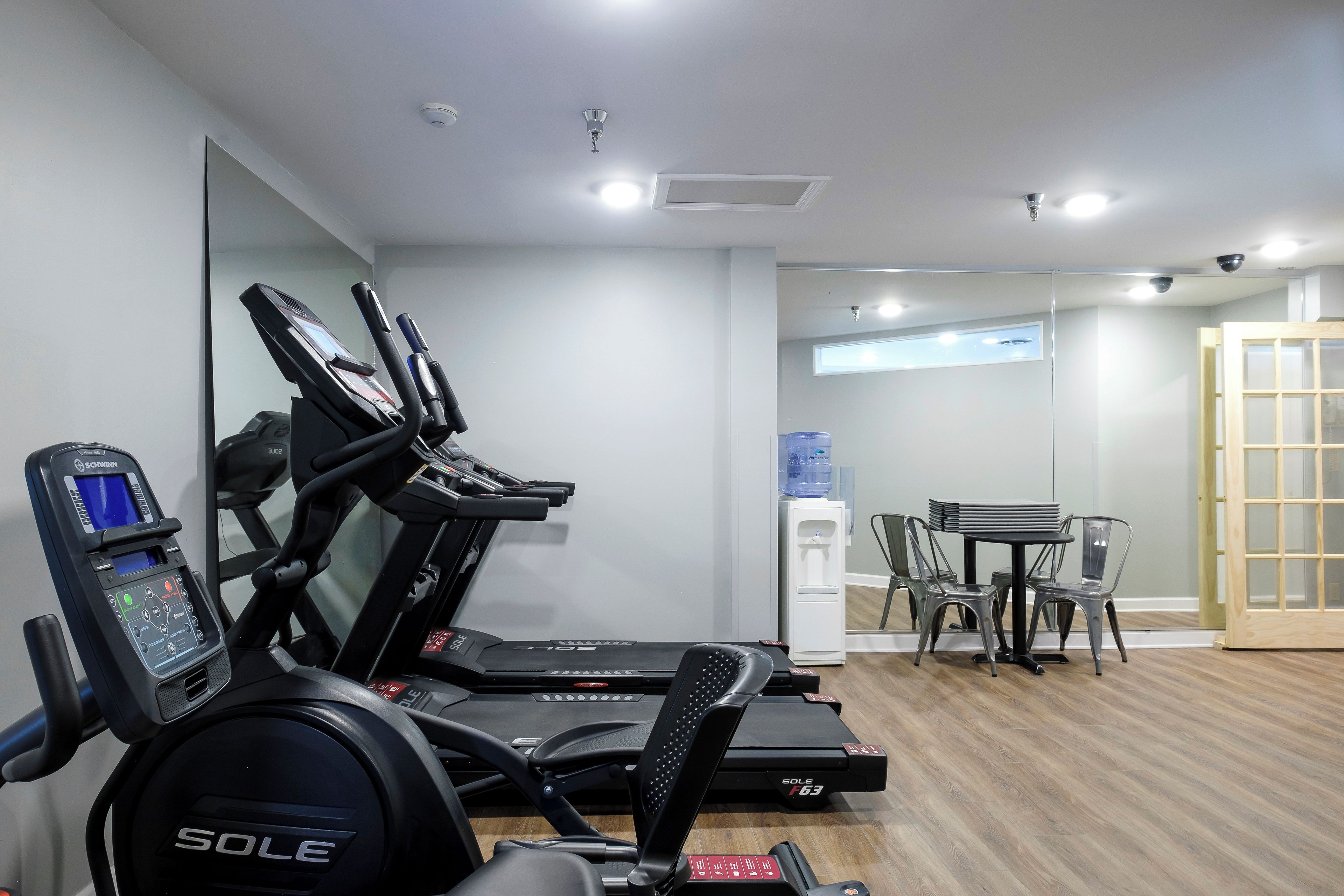 A gym with treadmills, a water dispenser, and a table with chairs.