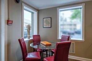 A dining area with a glass table and red chairs, a fire alarm, and a framed map on the wall. - Red Roof Inn & Suites Herkimer (Herkimer)
