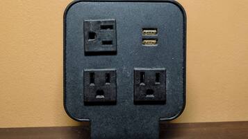 Een zwarte stekkerdoos met vier stopcontacten en een USB-poort, bevestigd aan een muur.