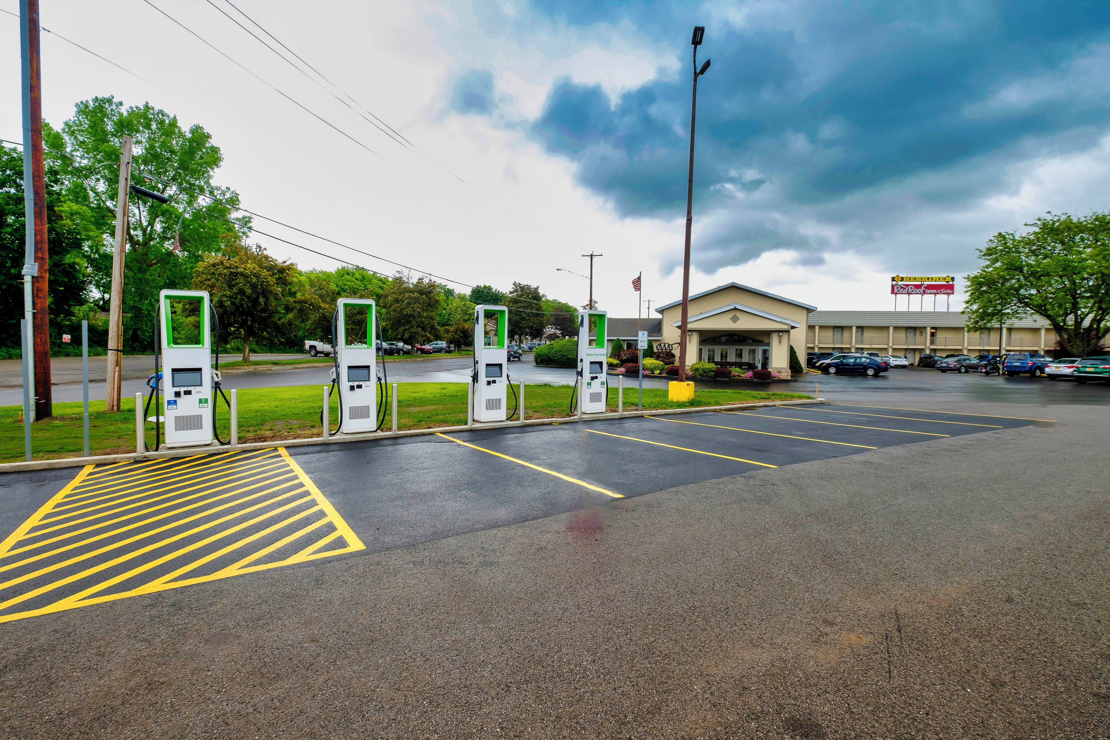 A parking lot with electric vehicle charging stations, a building with a sign, and a clear sky.