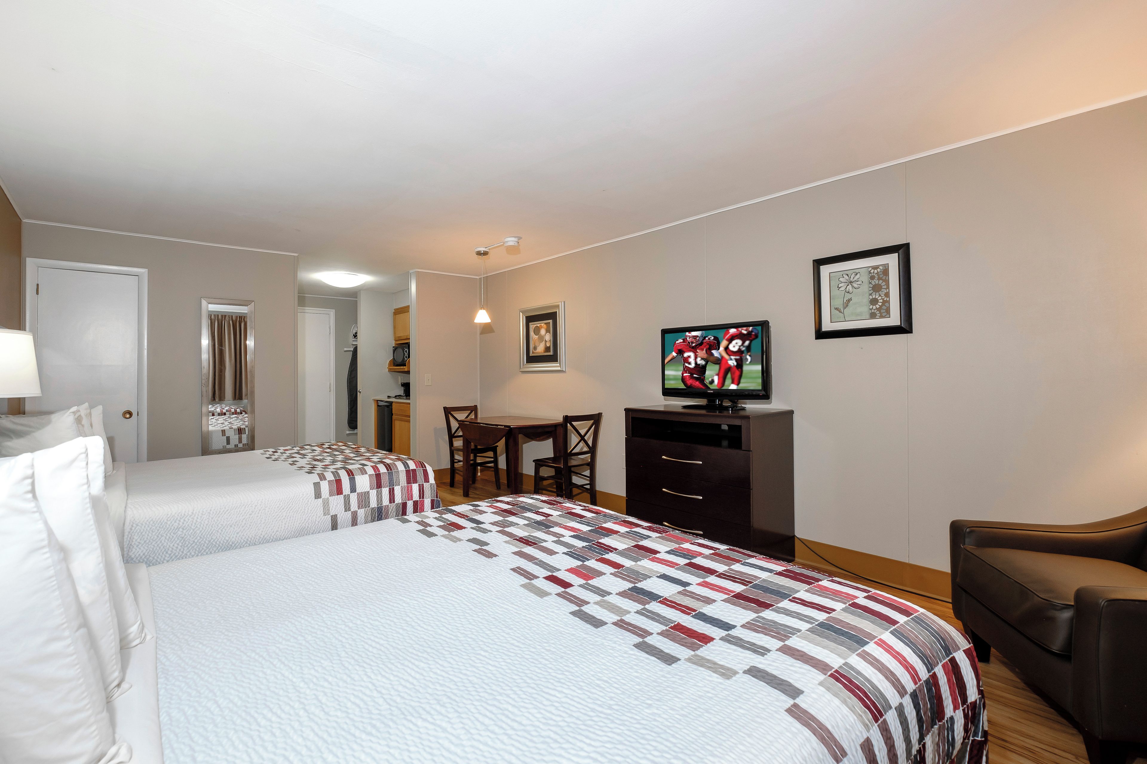 A hotel room with two beds, a TV, a desk, and a chair.