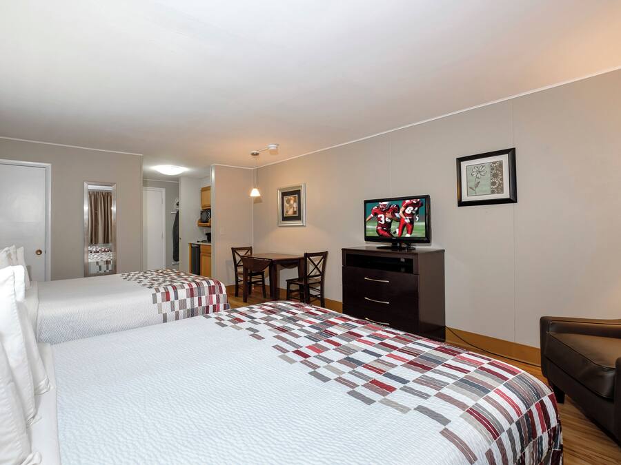 A hotel room with two beds, a TV, a desk, and a chair.