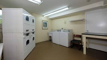 A laundry room with stacked washers and dryers, a small table, and a chair.