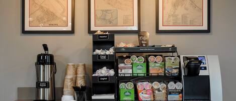 Una estación de café con una máquina de café, tazas y una variedad de cápsulas de café.