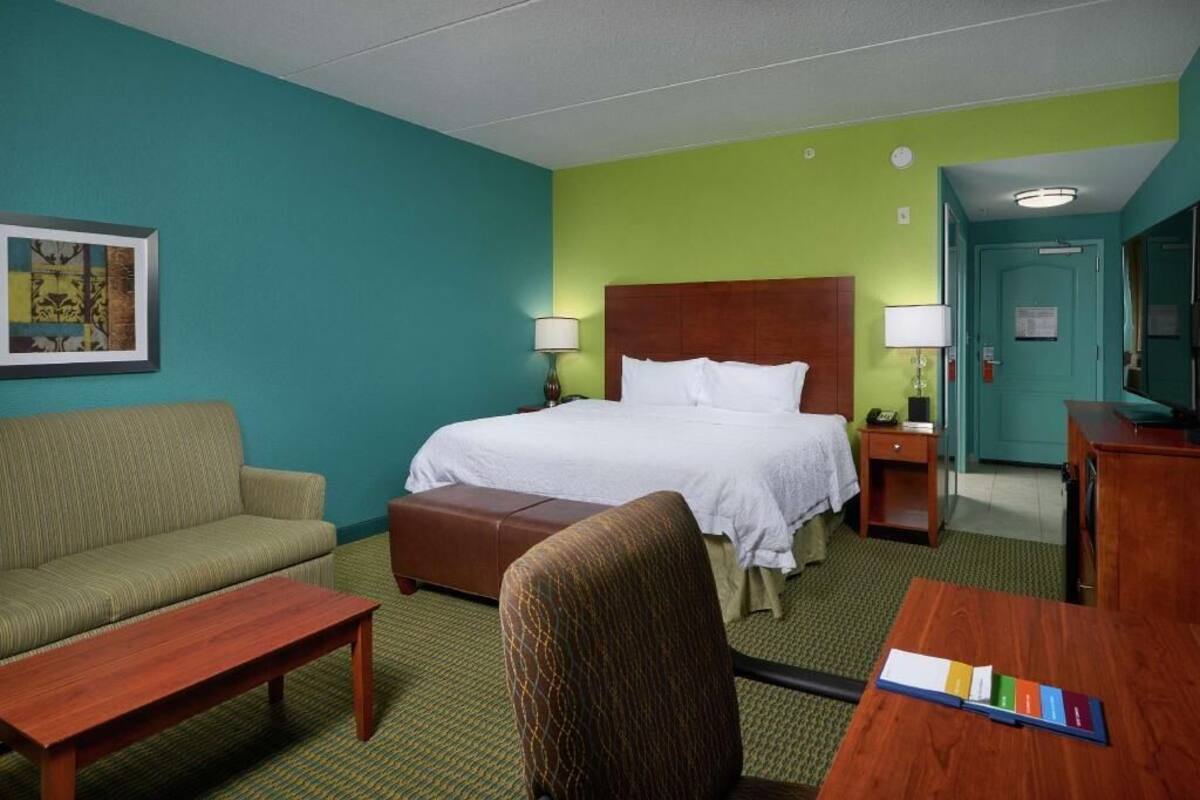 A hotel room with a bed, a sofa, a desk, and a chair.