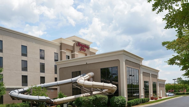 A Hampton Inn hotel with a large, curved water slide structure in front.