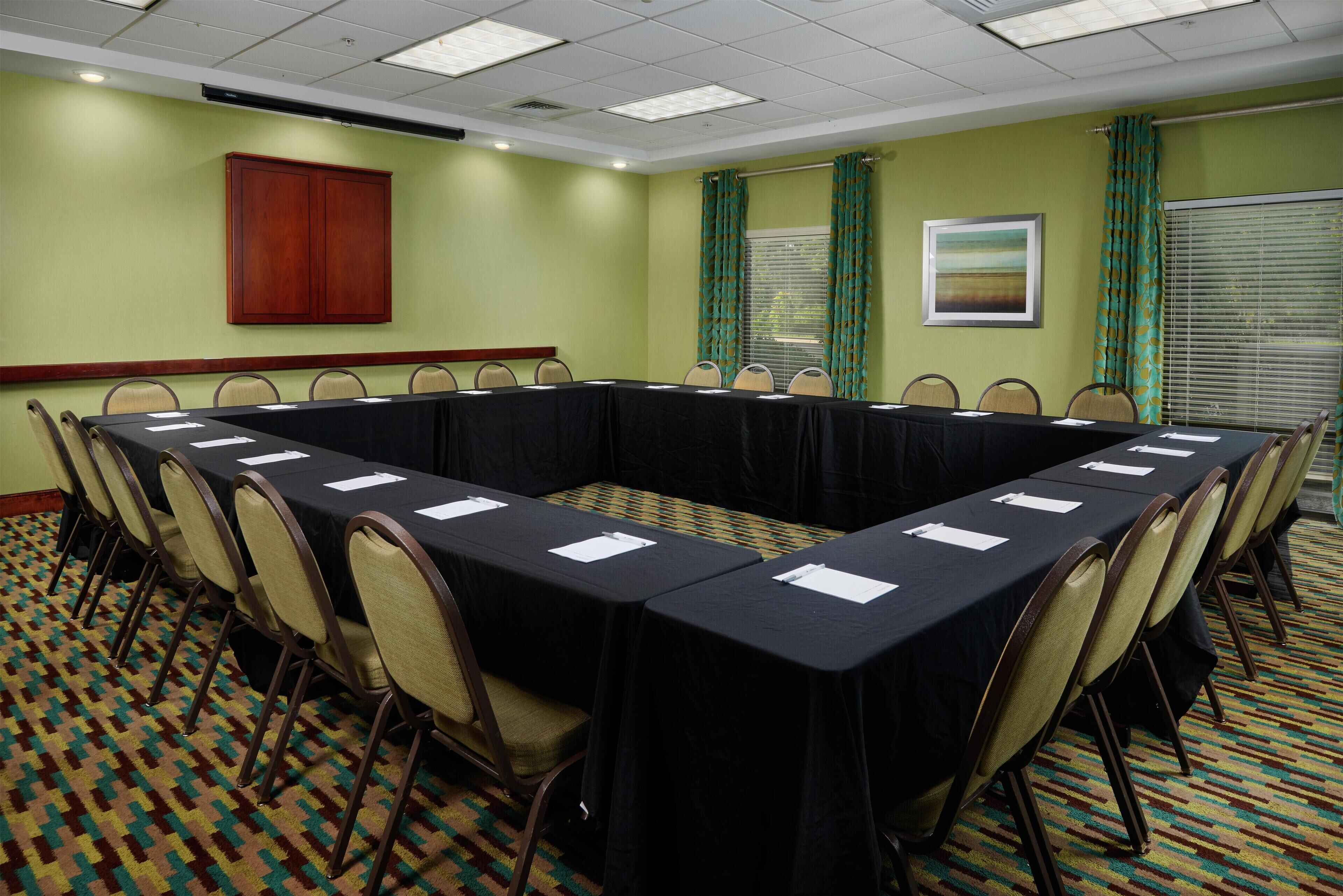 A conference room with a long table, chairs, and a cabinet.