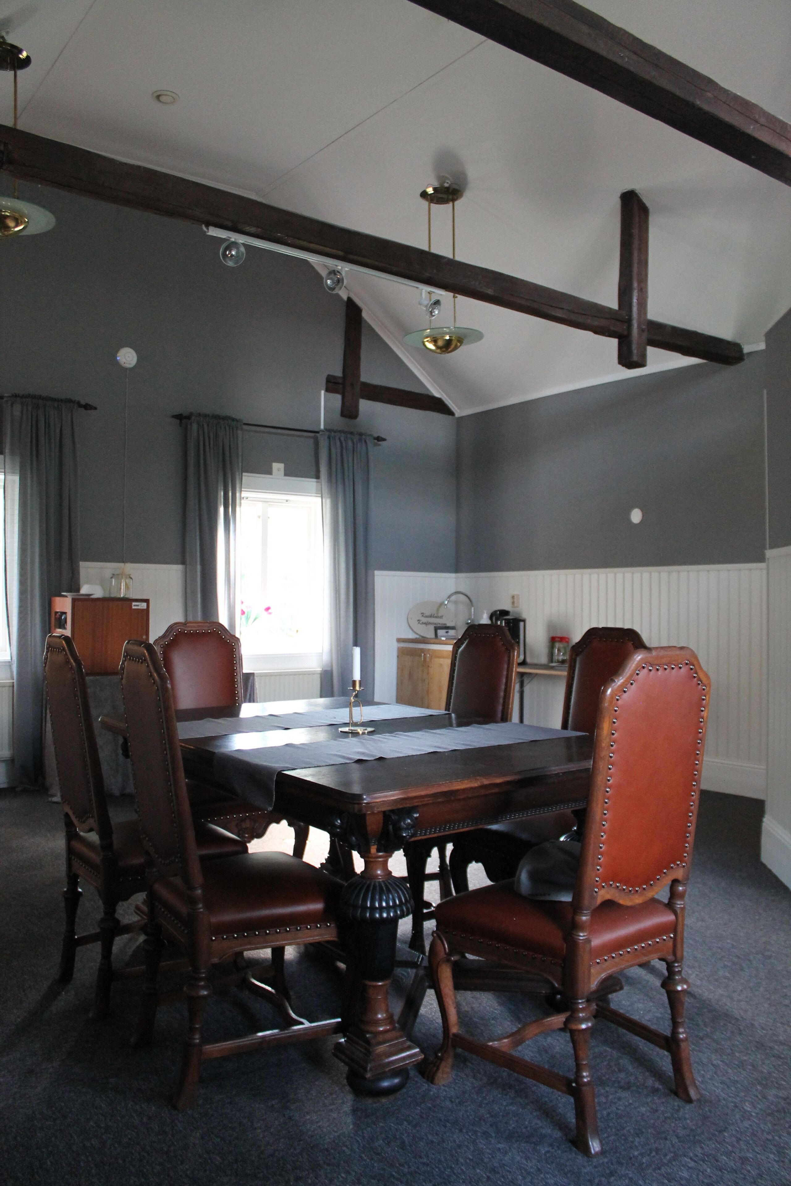 Une salle à manger avec une grande table en bois, six chaises rembourrées et un lustre.