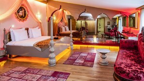 A luxurious bedroom with a canopy bed, a sitting area with a red sofa, and a dining area with a red table. - Hotel Sultania - Boutique Class (Istanbul)