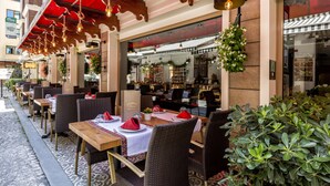 An outdoor dining area with tables and chairs, a red awning, and hanging lights. - Hotel Sultania - Boutique Class (Istanbul)