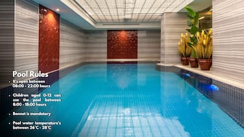 Een binnenzwembad, ligstoelen bij het zwembad