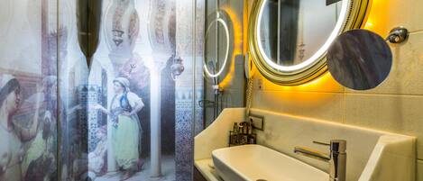 A bathroom with a large mirror, a sink, and a shower area.