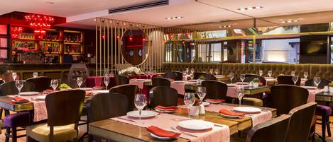 A restaurant with multiple dining tables, chairs, and a bar area.