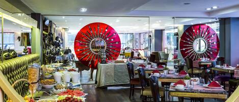 A dining area with a buffet setup, large red decorative mirrors, and a variety of food items.