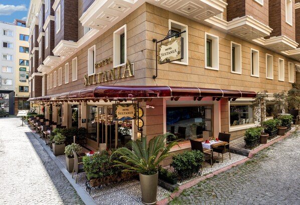 A hotel with outdoor seating, a sign reading "Hotel Sultania," and a cobblestone street. - Hotel Sultania - Boutique Class (Istanbul)