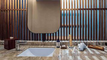 Un baño moderno con un espejo grande, encimera de mármol y paneles de madera.