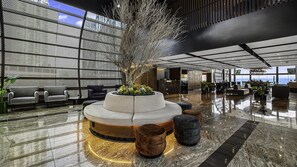 Un lobby moderno con zona de estar central, mostrador de recepción y bar.