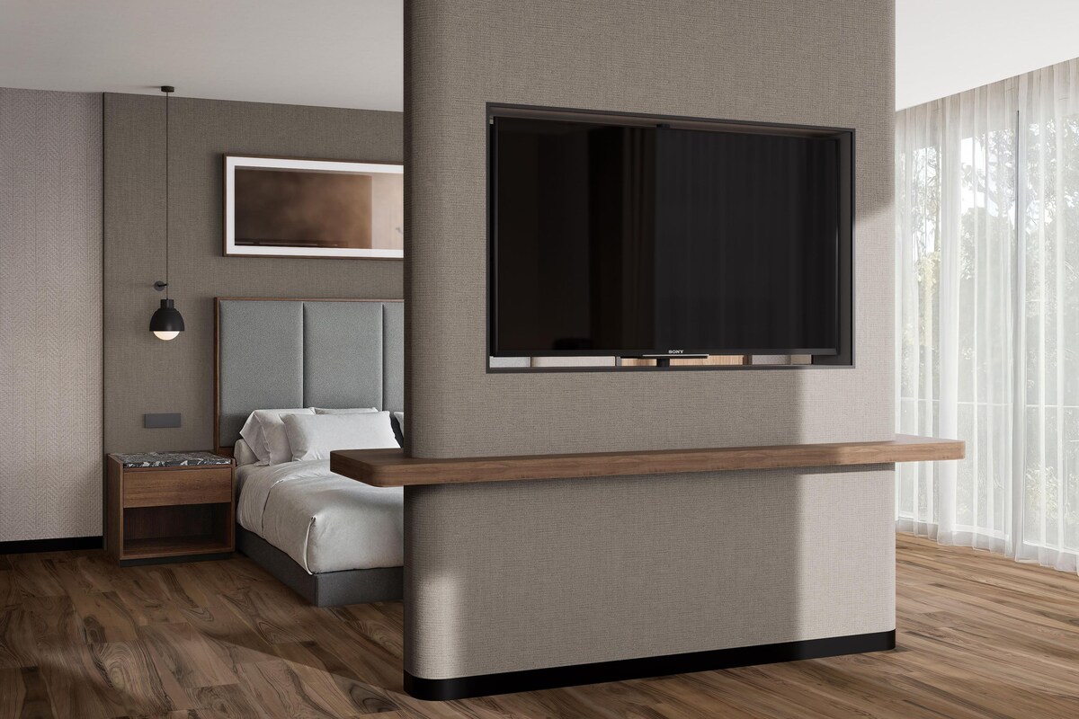 Un dormitorio moderno con una cama, una mesita de noche, un televisor montado y un ventanal grande.