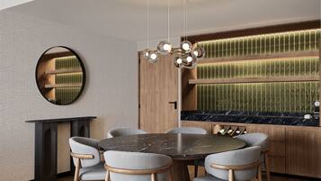 Un comedor moderno con una mesa redonda, seis sillas, un espejo circular y una encimera de cocina empotrada con salpicadero verde.
