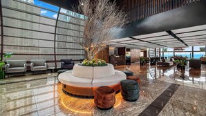 A modern lobby with a central seating area, a reception desk, and a bar. - Hilton Queretaro (Querétaro)