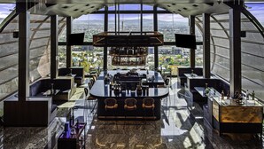 A high-rise bar with a panoramic city view, featuring a bar counter, seating, and a large window. - Hilton Queretaro (Querétaro)