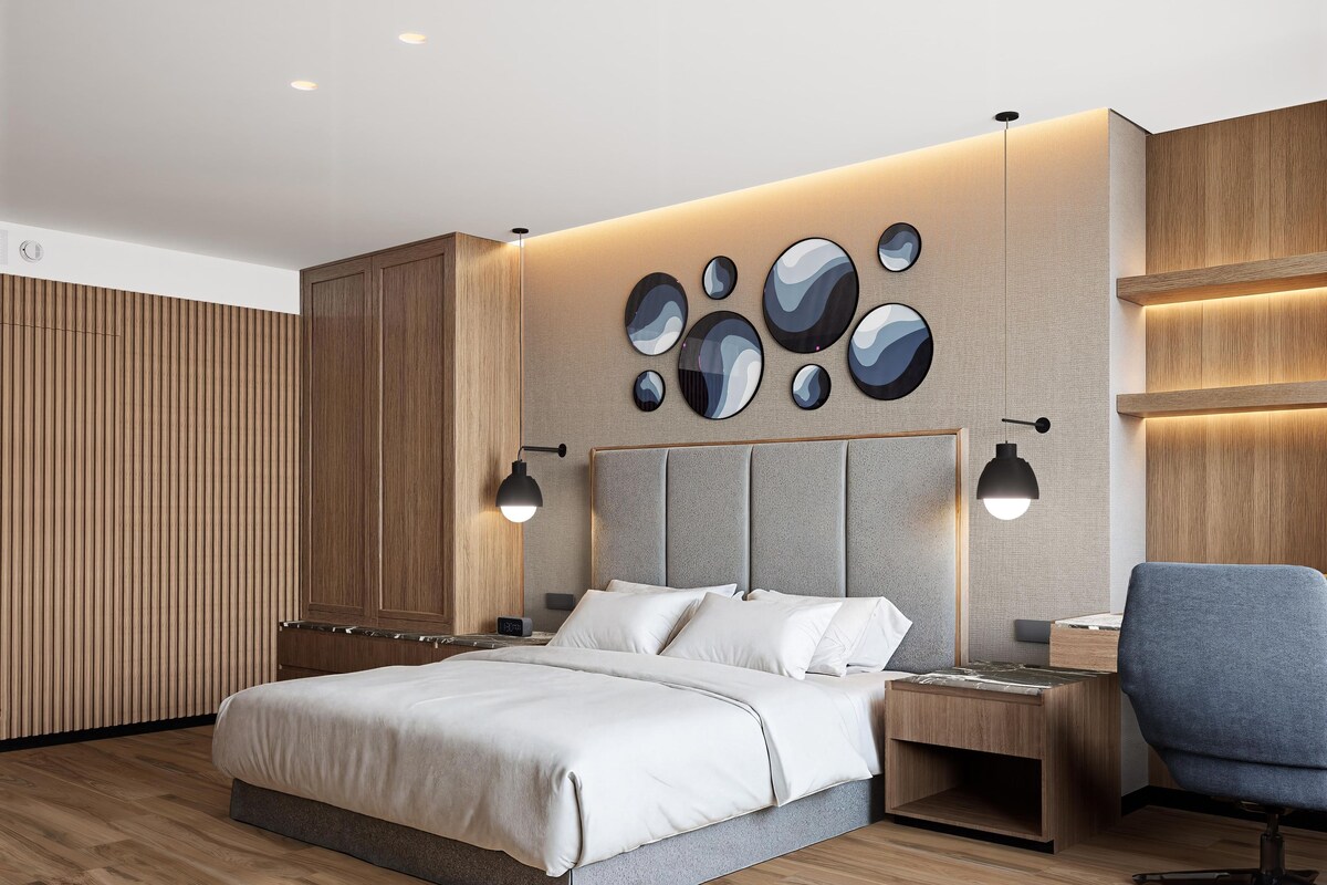 Un dormitorio moderno con cama, mesitas de noche, un escritorio y una silla.