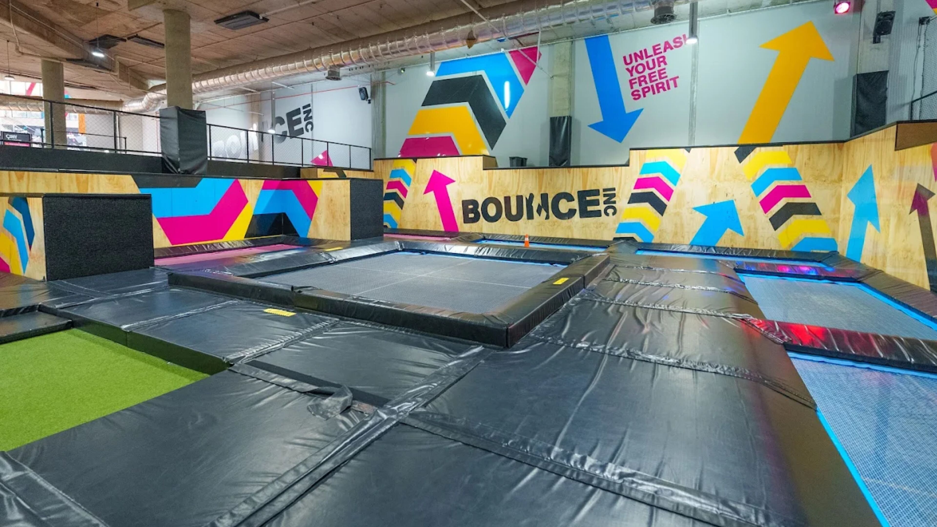 An indoor trampoline area with multiple trampolines and colorful wall decorations.