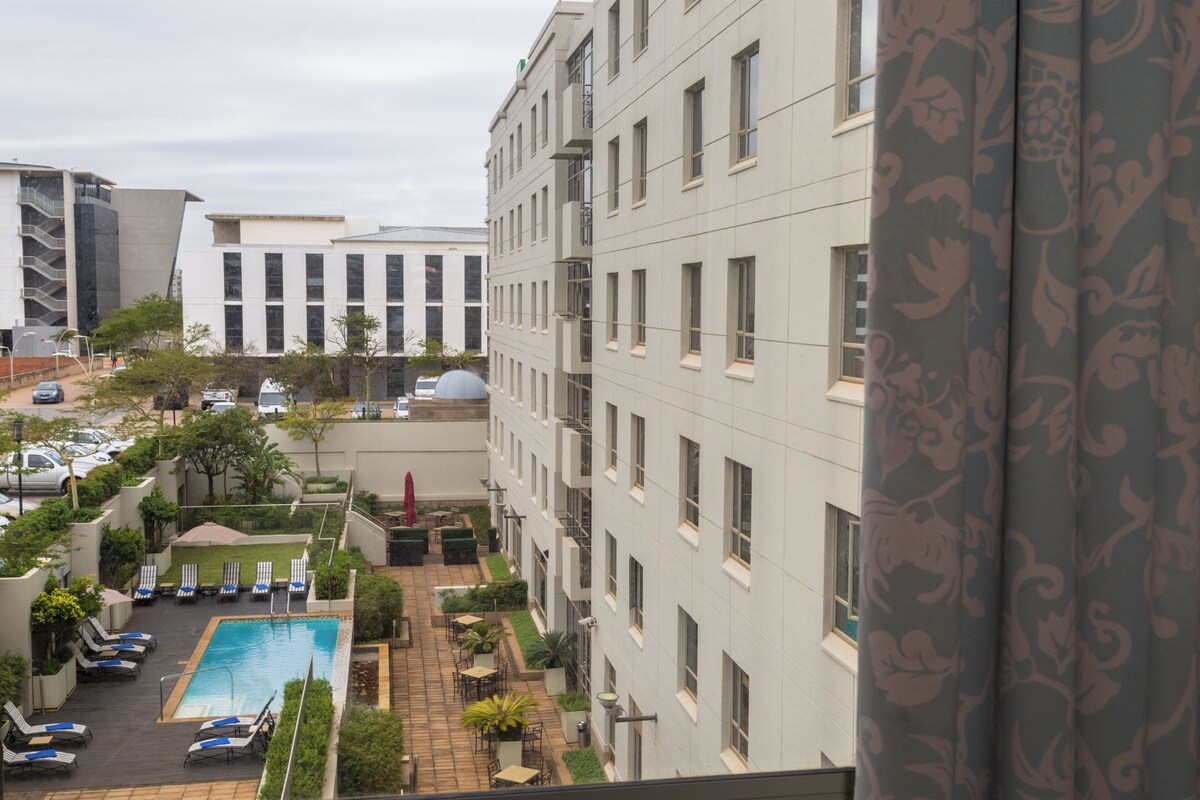 A residential building with a swimming pool, outdoor seating, and a parking area.