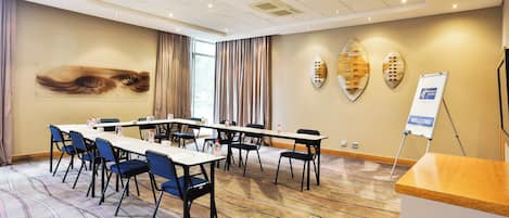A conference room with a long table, chairs, a podium, and a welcome sign.