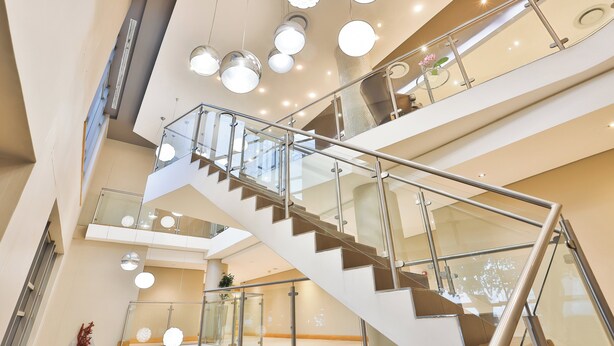 A multi-level interior with a central staircase, glass railings, and modern lighting fixtures. - Holiday Inn Express Durban - Umhlanga by IHG (Umhlanga)