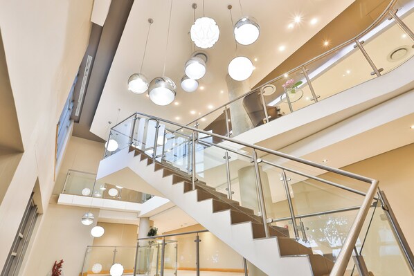 A multi-level interior with a central staircase, glass railings, and modern lighting fixtures. - Holiday Inn Express Durban - Umhlanga by IHG (Umhlanga)