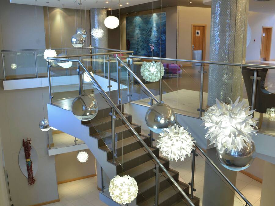 A modern interior with a glass staircase, metal railings, and contemporary lighting fixtures.