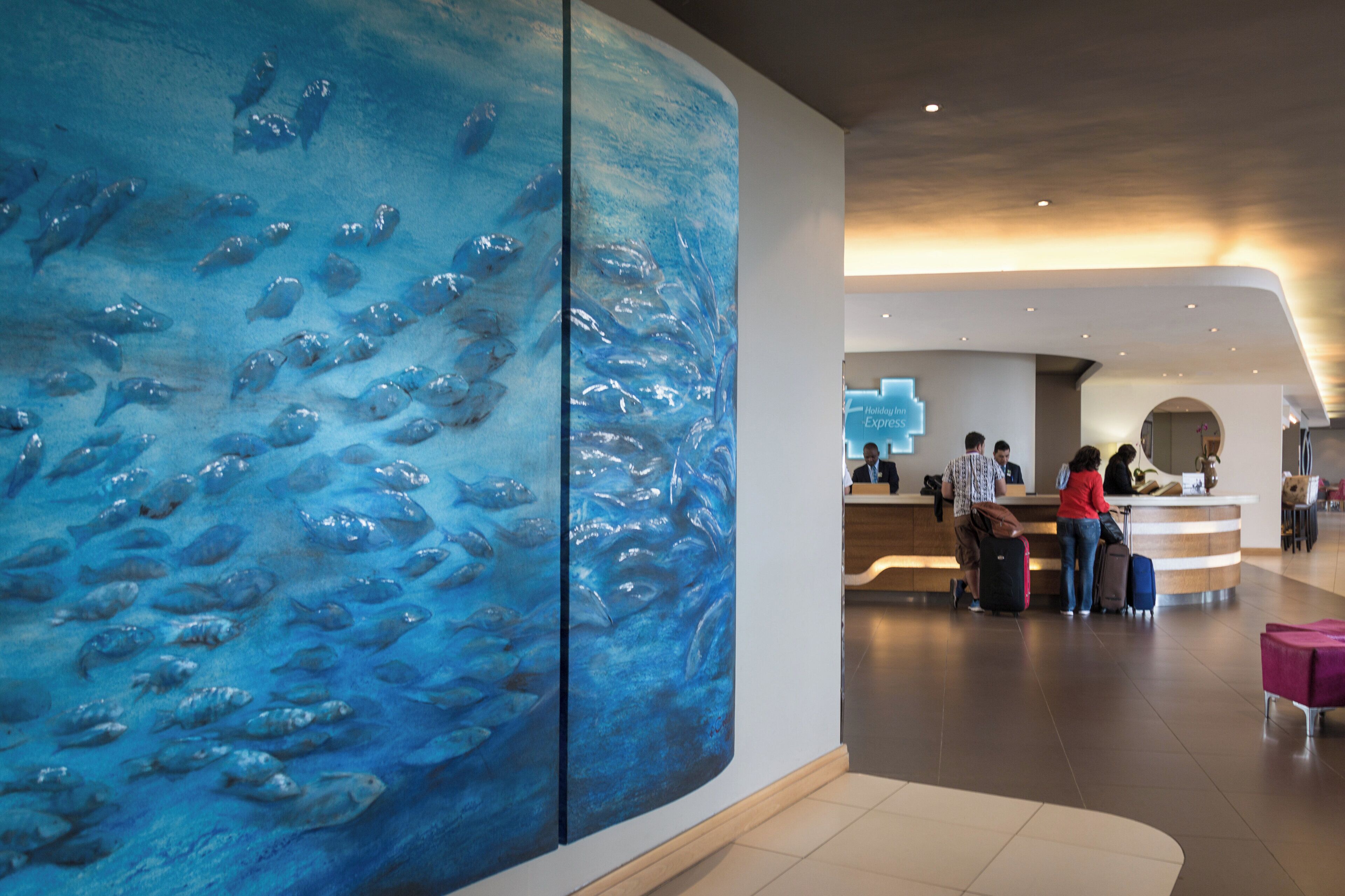 A reception area with a large wall mural of fish, a reception desk, and a check-in counter.