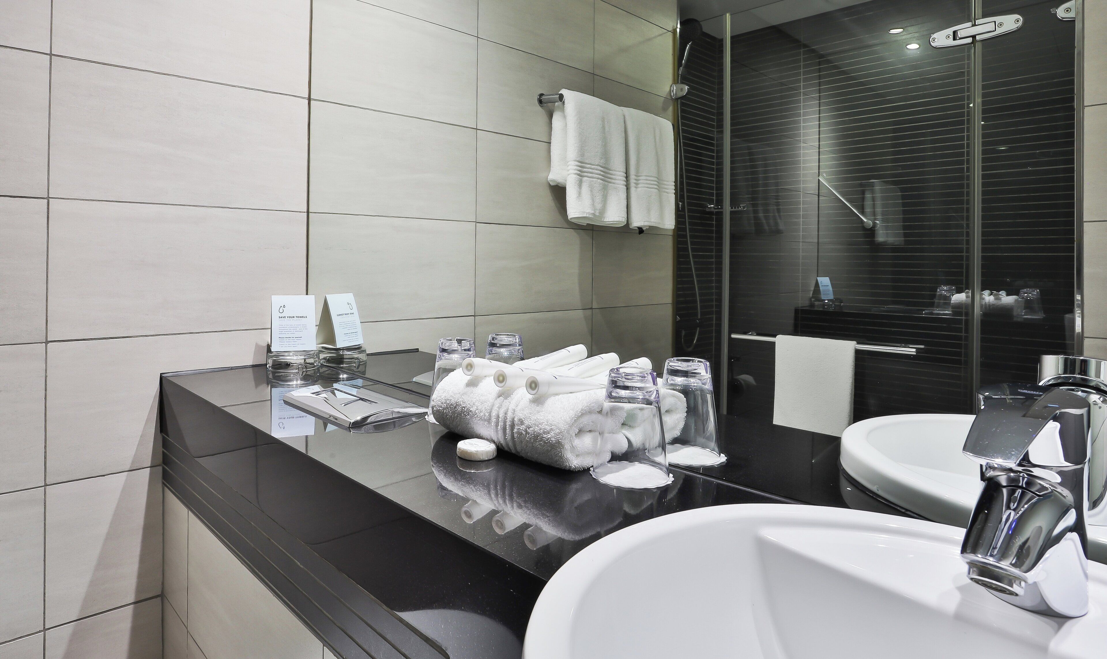 A modern bathroom with a black countertop, two sinks, and a glass shower enclosure.