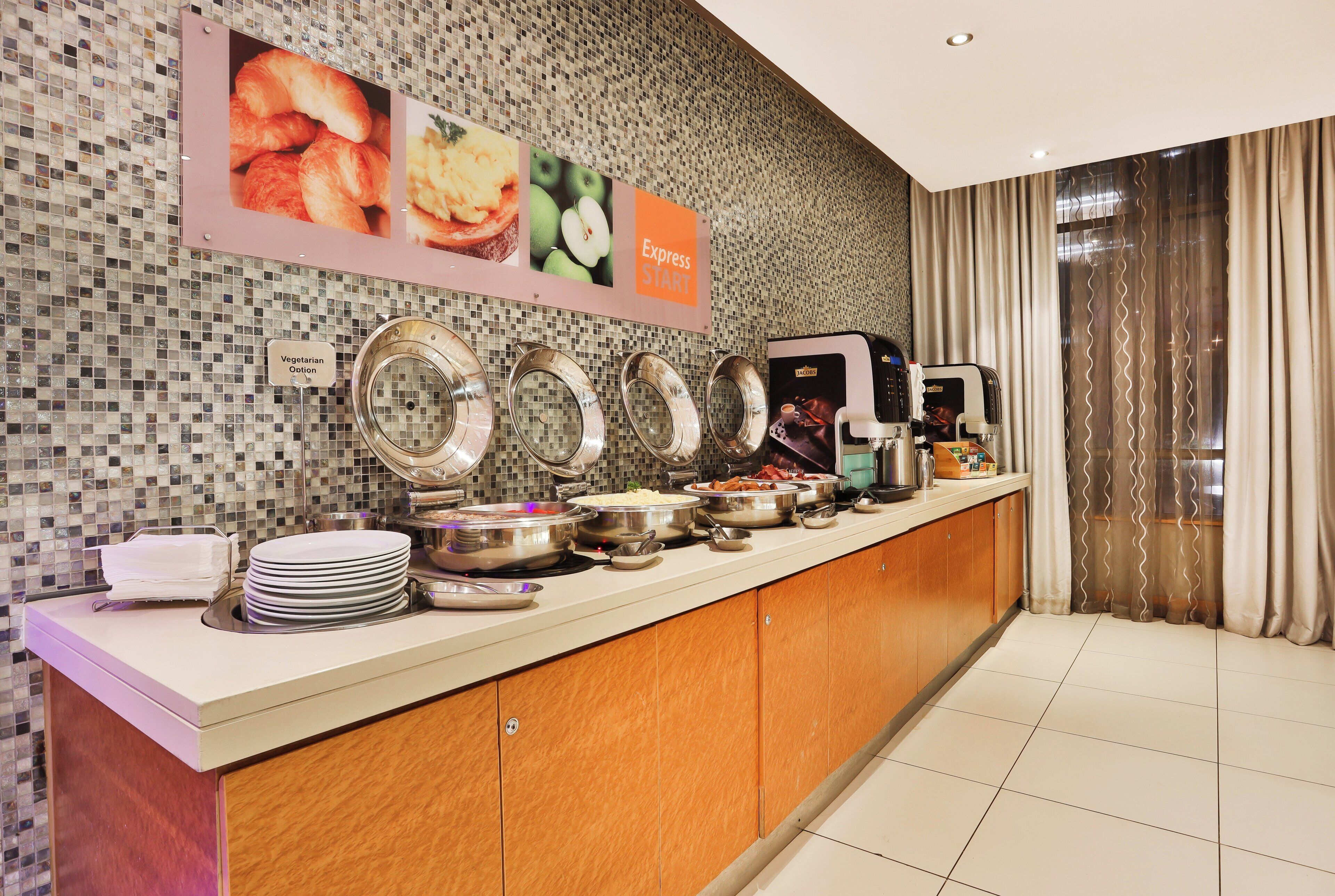 A buffet counter with various food containers, a sign indicating vegetarian options, and a coffee machine.