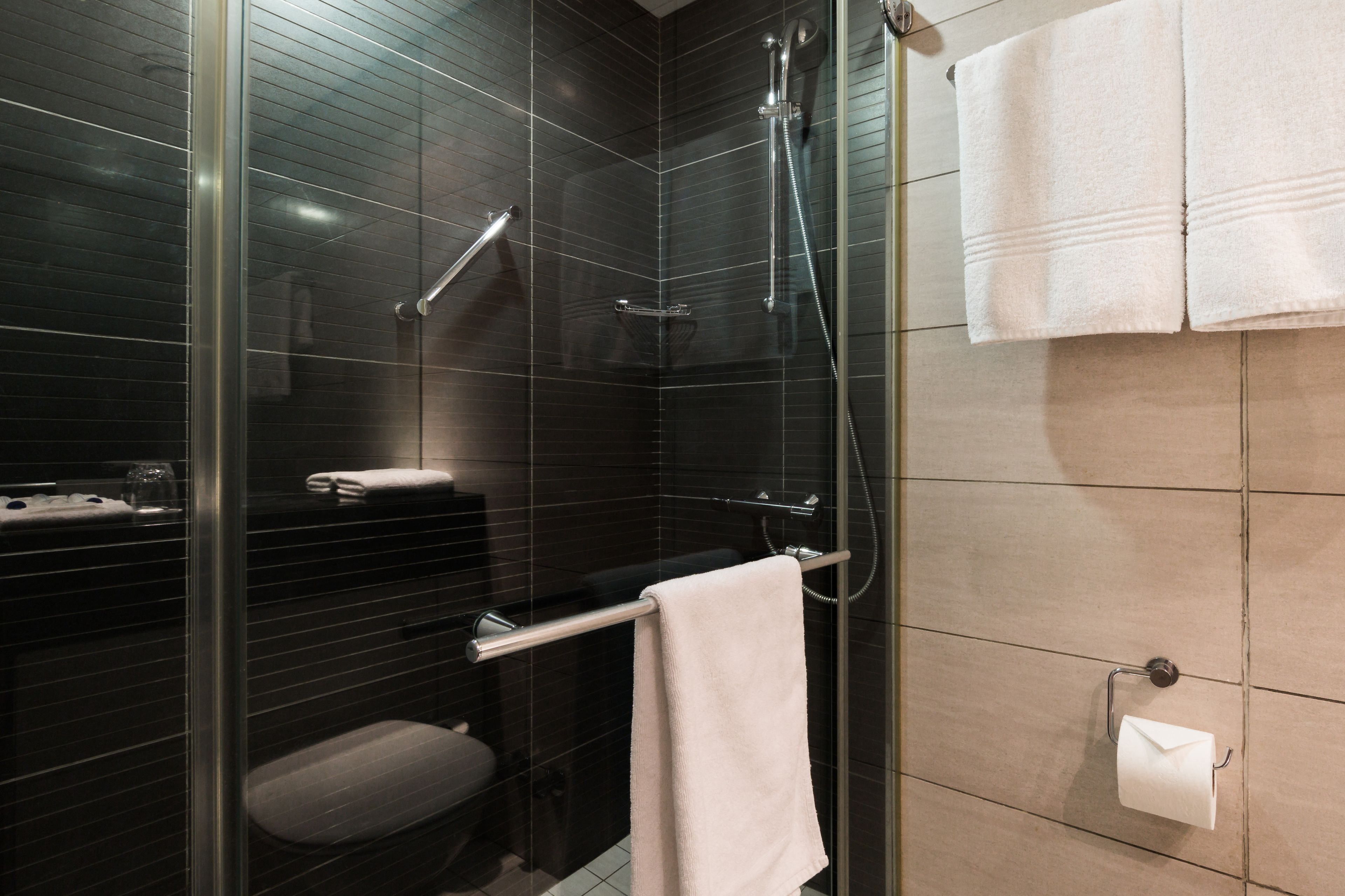 A modern bathroom with a glass-enclosed shower, a toilet, and a towel rack.