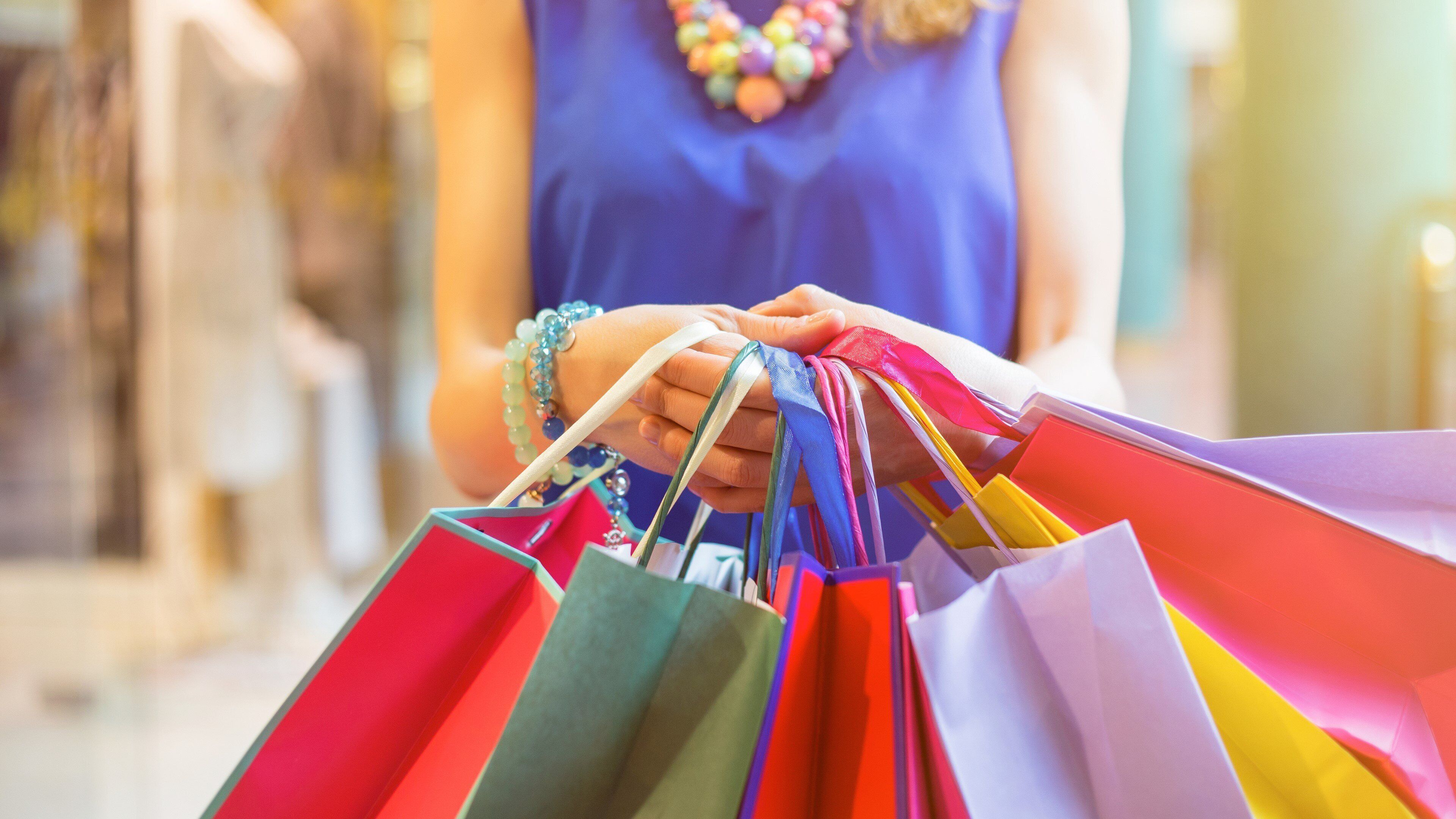 A person holding colorful shopping bags.