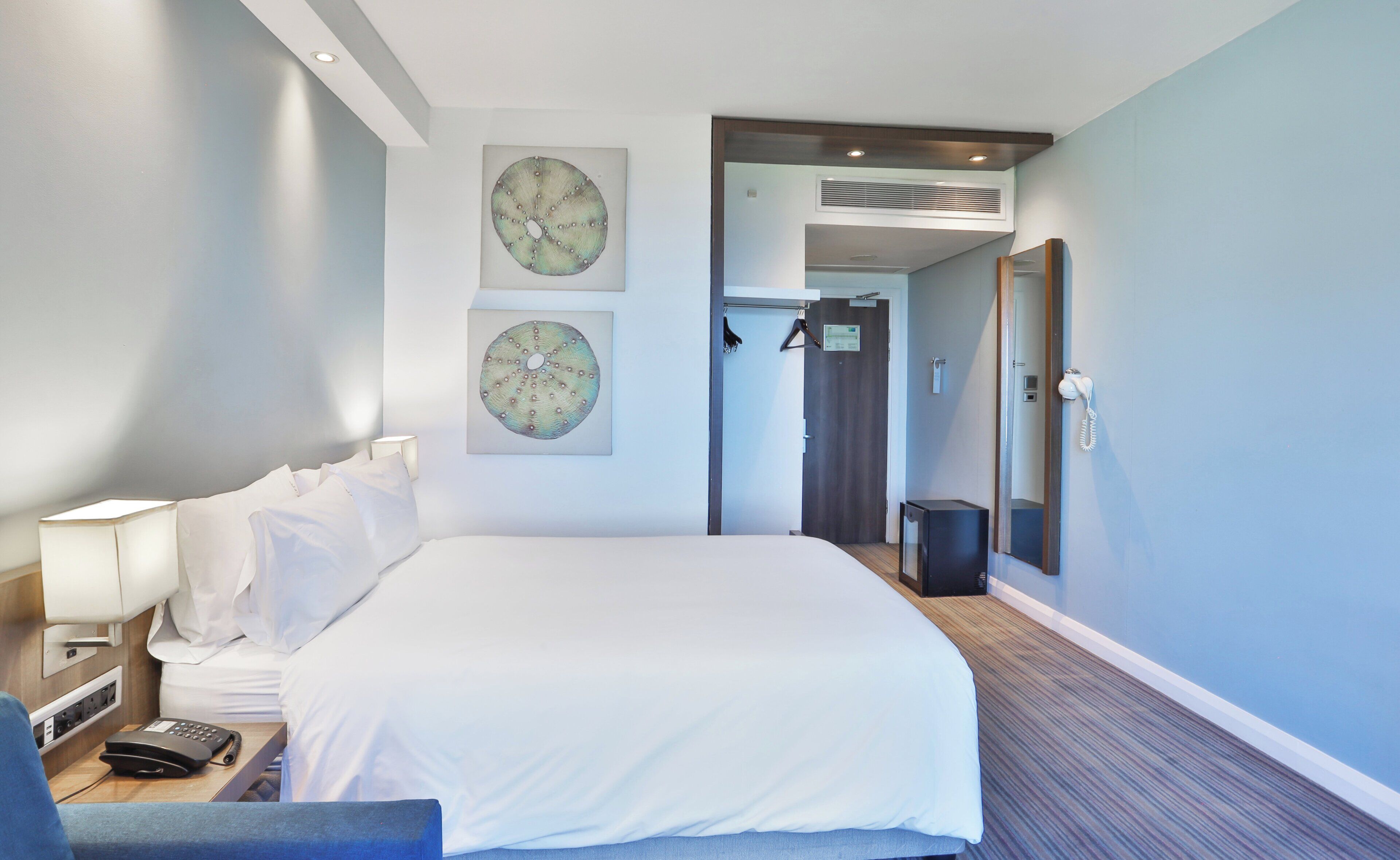 Une chambre d’hôtel avec un lit, un bureau avec un téléphone et un miroir.