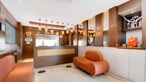 A modern hotel lobby with a reception desk, seating area, and decorative elements. - La Sara Hometel (Bengaluru)