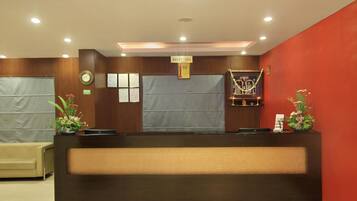 A reception area with a wooden reception desk, a clock, and a framed certificate on the wall.