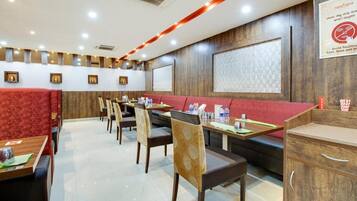Un restaurante con cabinas y mesas, paneles de madera y un cartel que recomienda no tocarse la cara.