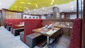A restaurant with booths and tables, featuring a modern ceiling design and wooden accents. - La Sara Hometel (Bengaluru)