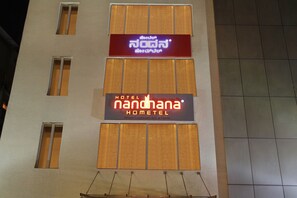 A hotel building with multiple windows and two prominent signs. - La Sara Hometel (Bengaluru)