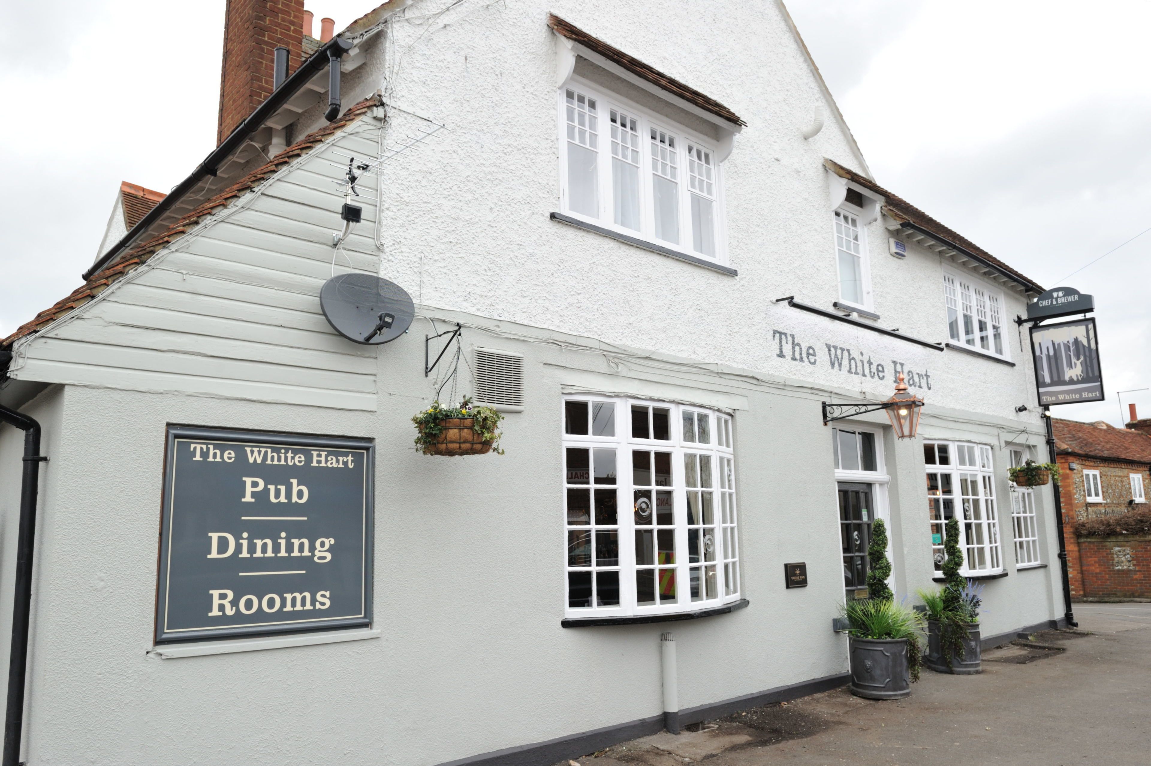 A white building with a sign reading "The White Hart Pub Dining Rooms."